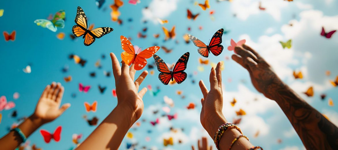 People's hands release colorful paper butterflies into the blue sky, symbolizing unity on Zero Discrimination Day